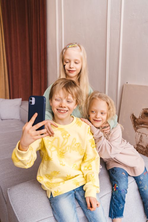 Free Three children taking a selfie together, showcasing friendship indoors. Stock Photo