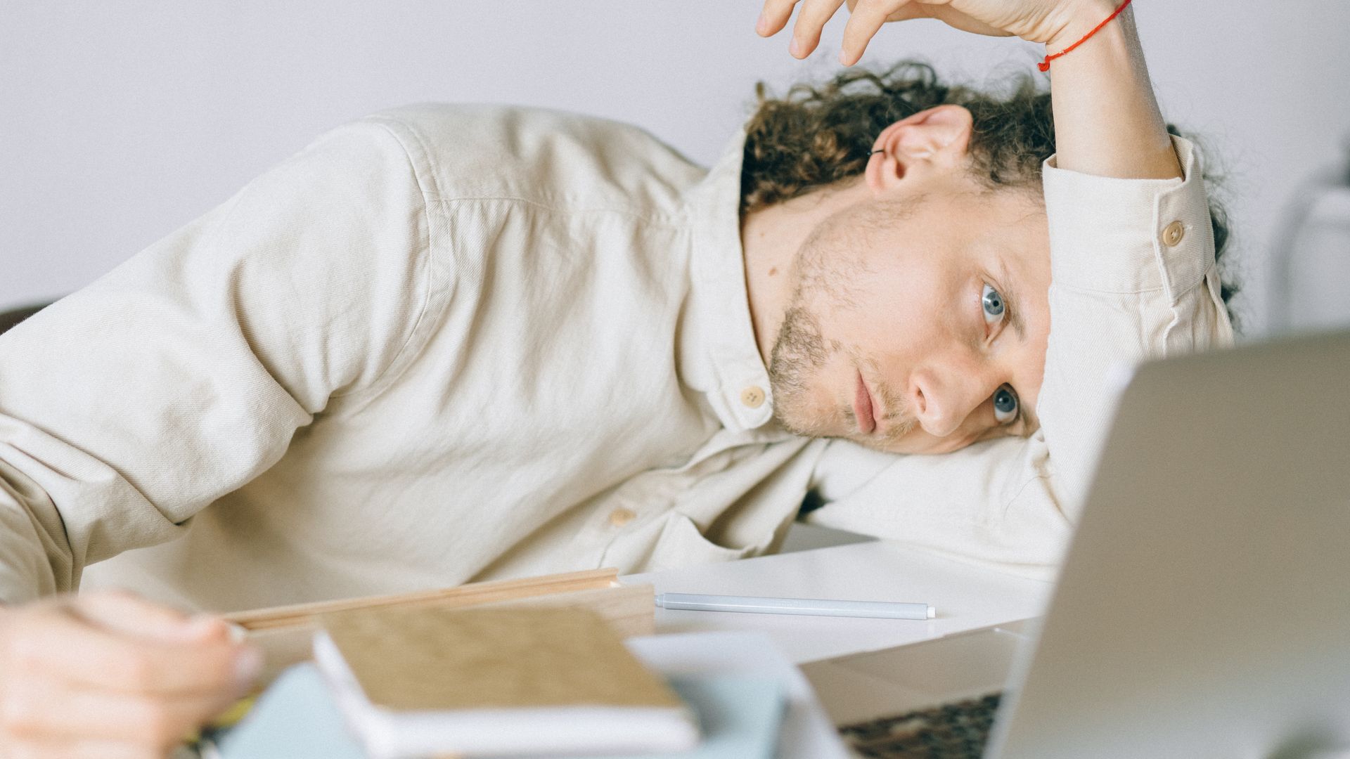 Modafinil for Long COVID Fatigue: Unlocking Energy A tired Caucasian man at a desk, showing signs of exhaustion and stress, exemplifying workplace burnout — modafinil for long covid fatigue