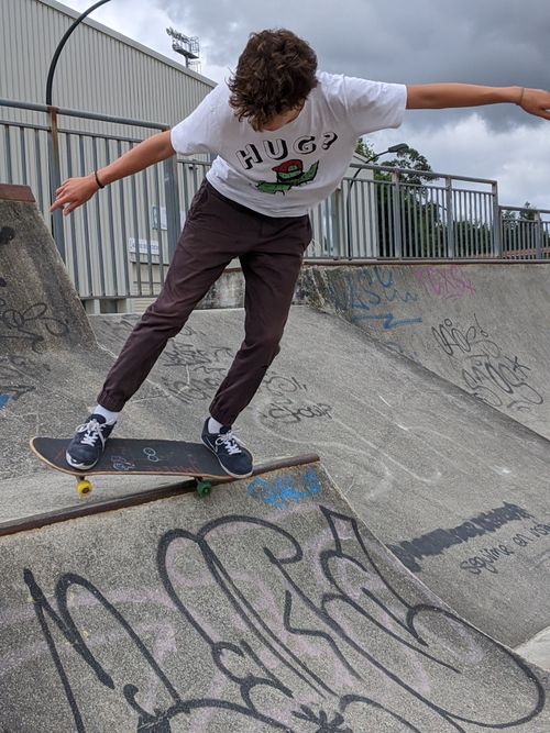 Free Teen skateboarder executing a trick on a skate ramp at an outdoor skatepark. Stock Photo