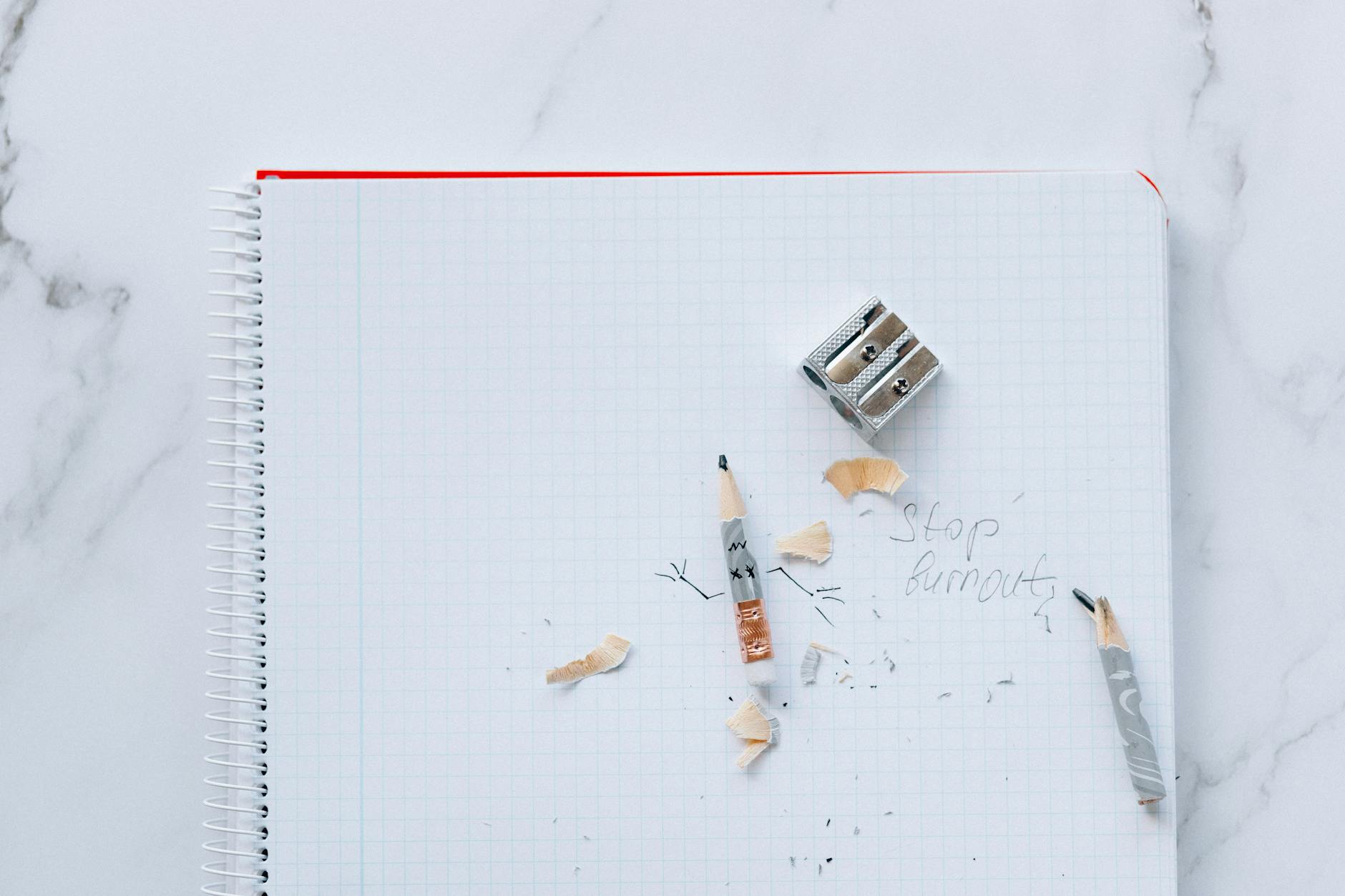 Spiral notebook with pencils, sharpener, and 'Stop burnout' written on paper.