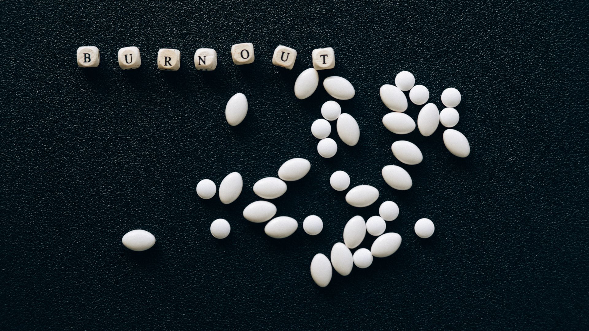 Modafinil Productivity Tips: Boosting Focus and Performance White pills arranged on a black surface spelling 'burnout', symbolizing stress and fatigue — modafinil productivity tips