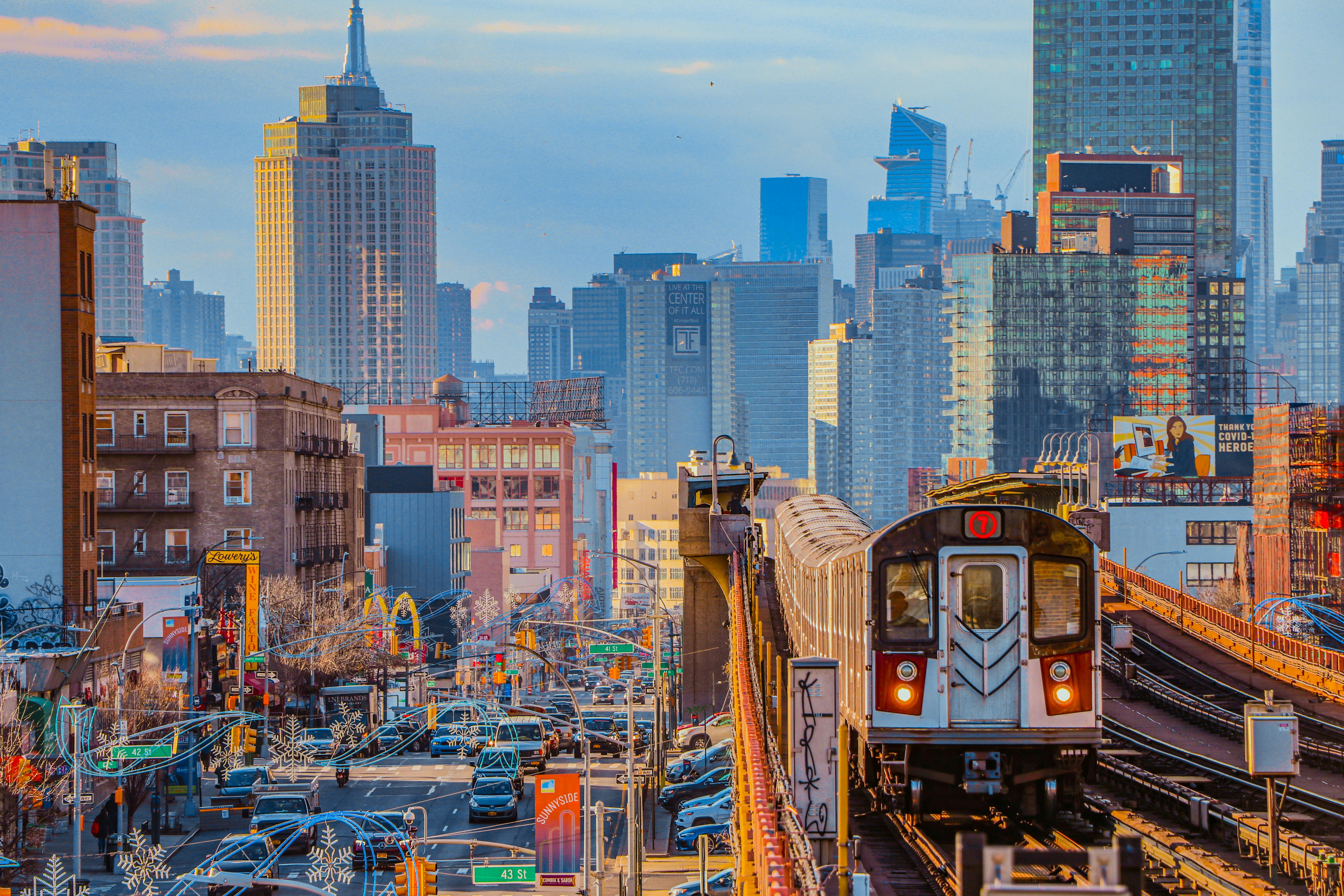 A vibrant view of New York City with a subway train amid skyscrapers at dusk.