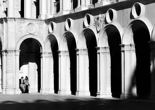 Couple Sitting Beside Arch Building