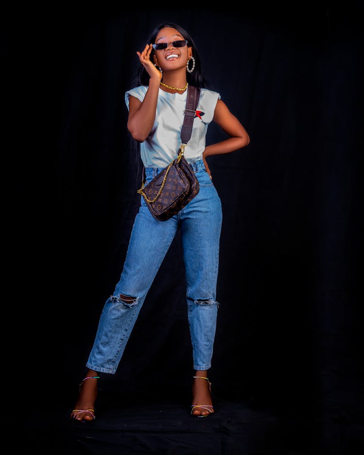 Fashionable Woman Wearing Jeans And A Designer Bag Posing And Smiling 