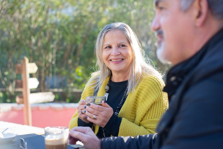 An Elderly Woman In Yellow Knitted Cardigan Smiling While Talking To The Man Beside Her