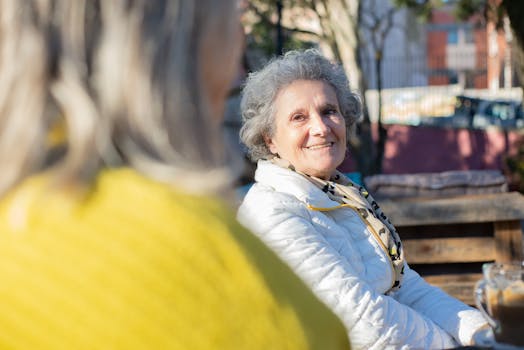 Cheerful senior women sitting outdoors in Portugal, embracing friendship and sunshine.