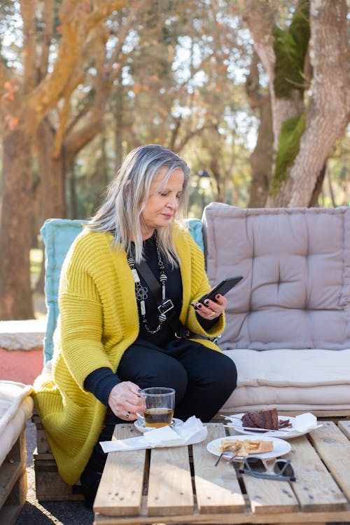 Free Woman Using a Cellphone While Having Tea Stock Photo