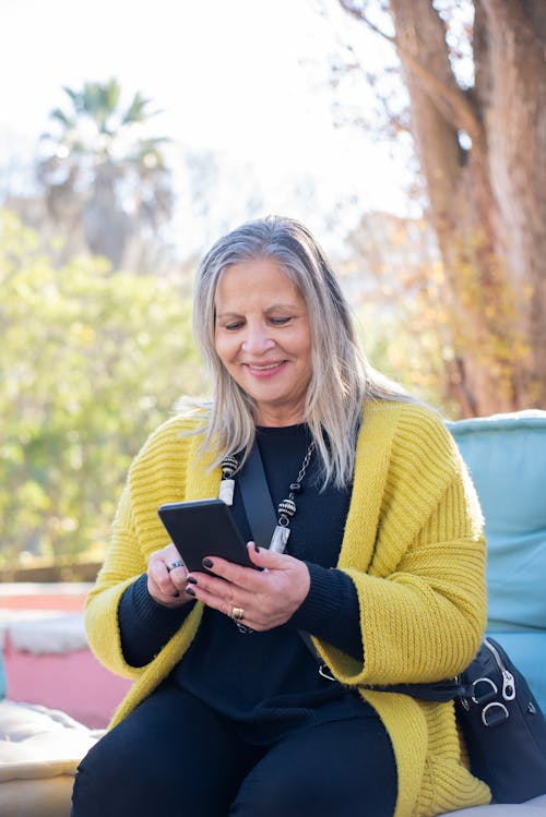 Free Smiling Woman Using a Smartphone Stock Photo