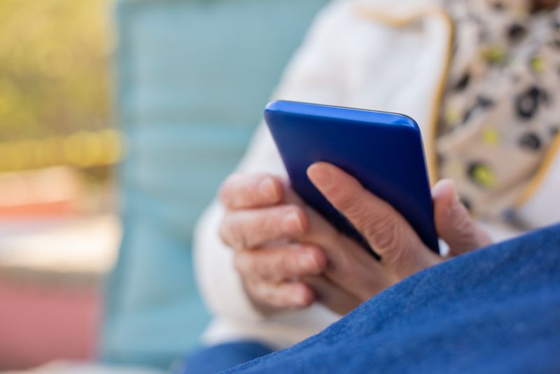 Senior adult typing a message on a smartphone outdoors