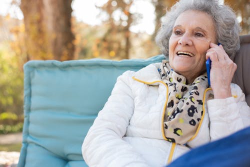 Free An Elderly Woman Leaning on Throw Pillow while Having a Phone Call Stock Photo