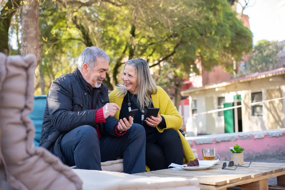 Couple de seniors souriant à l'extérieur, smartphone à la main