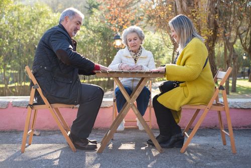 Free Three seniors enjoying a sunny day playing dominoes outdoors in a Portuguese park. Stock Photo