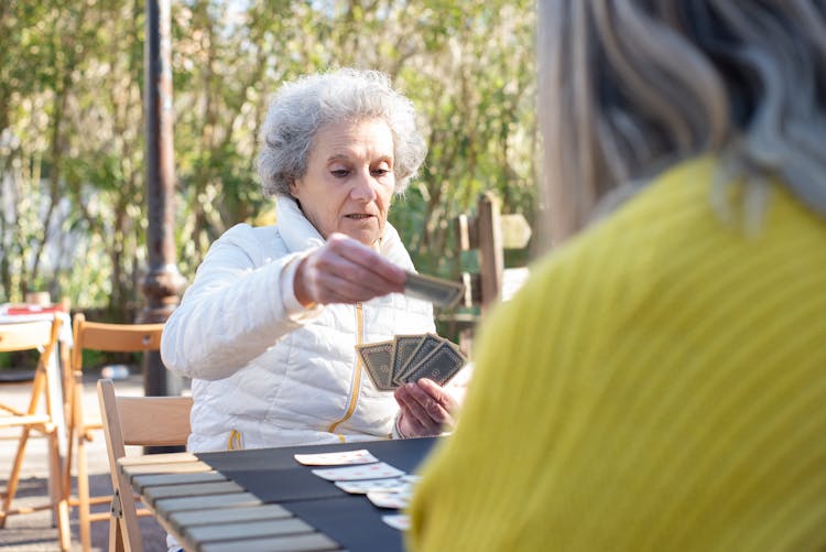 Elderly Woman In White Jacket Holding Playing Cards