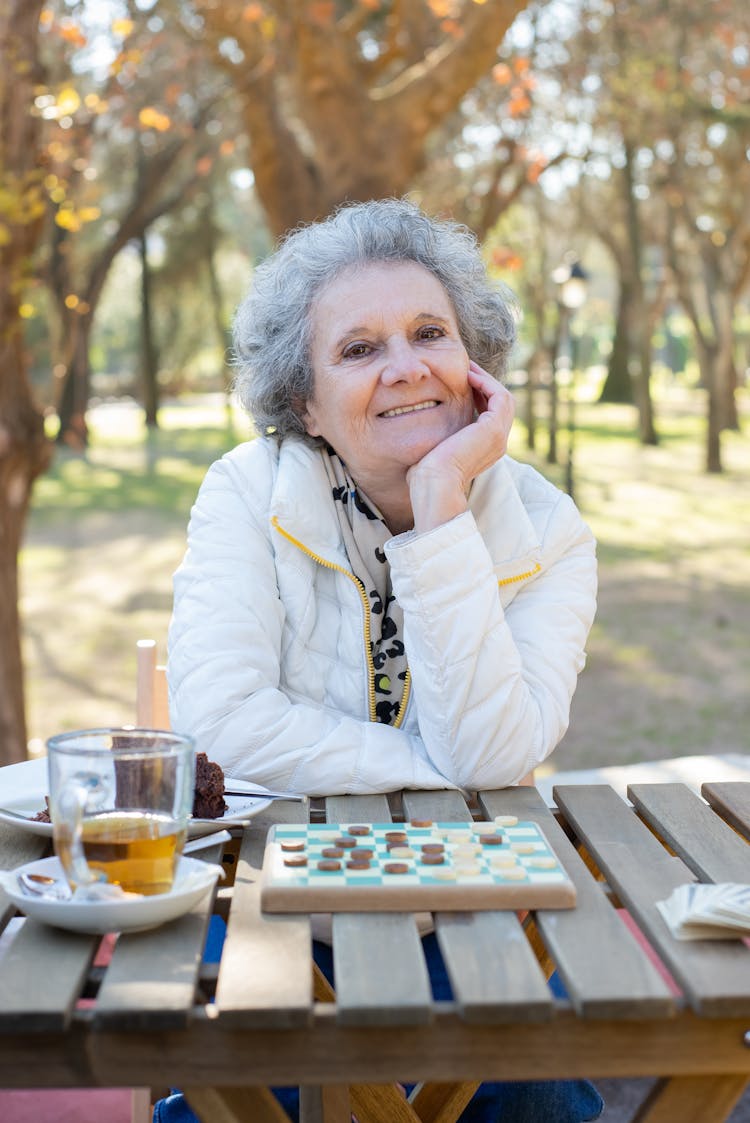 Elderly Woman Sitting By The Table Playing Board Game