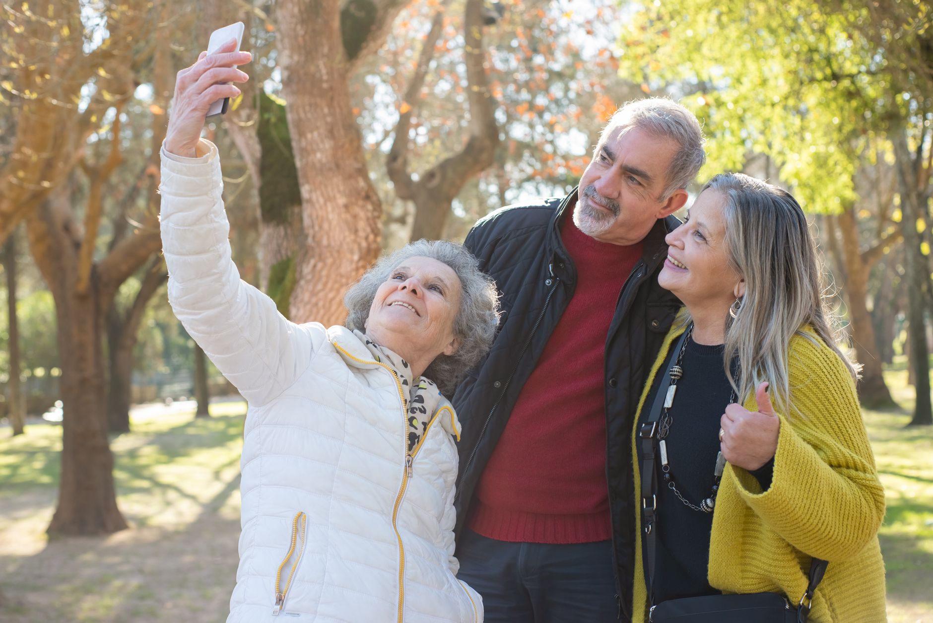 Group of cheerful seniors taking a selfie together outdoors, capturing a moment of joy.