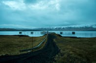 在多云的天空下，冰岛湖上的码头被雪山环绕，景色宁静