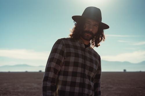 Free Stylish man in plaid shirt and fedora in a serene desert landscape. Stock Photo