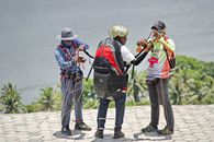 Person wearing Paragliding Sports Equipment assisted by Personnel