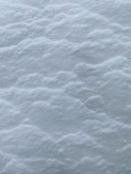 Detailed close-up of snow surface displaying delicate textures and patterns, evoking a serene winter scene.