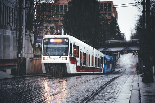 Free Tram moving along cobbled street with reflection of light of headlights in wet surface in daytime during overcast Stock Photo