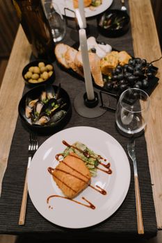 Sophisticated table setting featuring a gourmet salmon dish with sides, under soft candlelight.