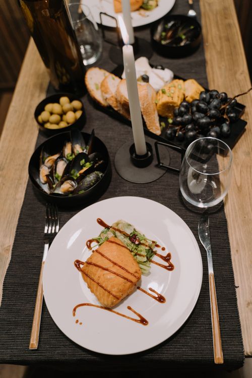 Free Sophisticated table setting featuring a gourmet salmon dish with sides, under soft candlelight. Stock Photo
