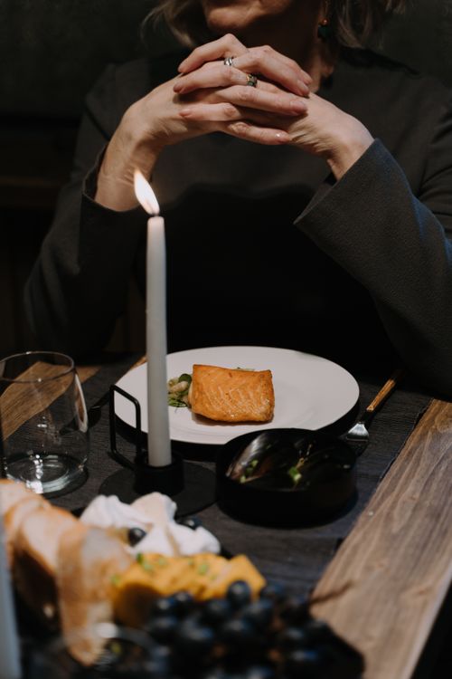 Free Elegant candlelit dinner setting with grilled salmon and a thoughtful woman. Stock Photo