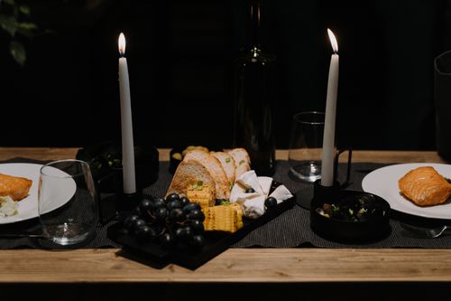 Free A romantic candlelit dinner setup featuring salmon, cheese, bread, and grapes for an intimate meal. Stock Photo