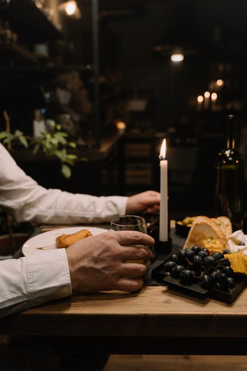 Free Elegant candlelit dinner setup with wine, grapes, and bread on a wooden table. Stock Photo