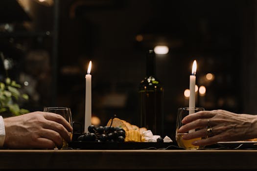 Intimate dinner setup with wine, cheese, and candles on a wooden table.