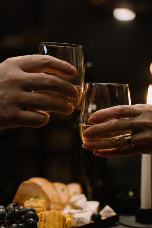 Free Two people clinking wine glasses over a candlelit dinner, creating a cozy and intimate atmosphere. Stock Photo