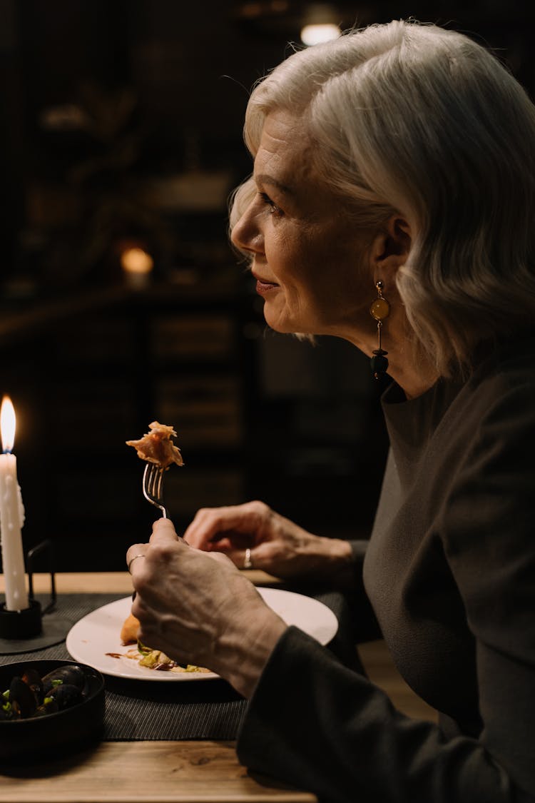 Woman Having Dinner On Table With Lighted Candle