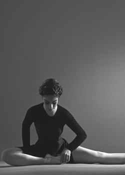 A graceful ballerina in a studio setting, captured in black and white, exuding elegance and focus.