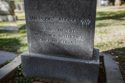 Free A stone tombstone with an engraved epitaph in a sunlit cemetery setting. Stock Photo