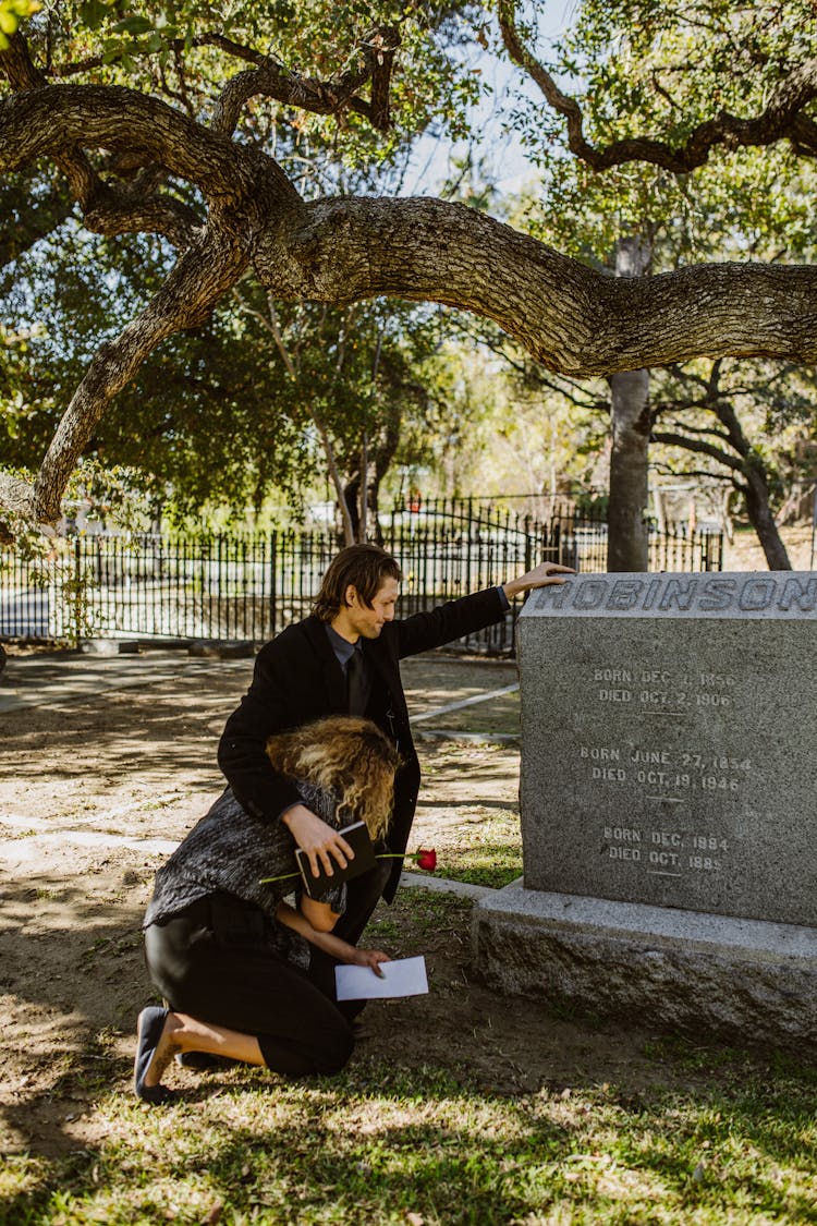 Grieving Couple Beside A Tombstone