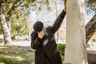 A Person in Black Jacket Standing beside Gray Concrete Structure
