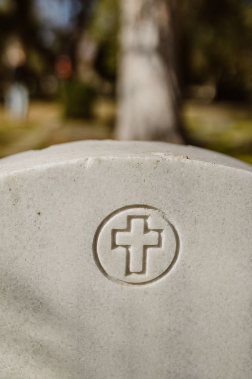 Free A detailed view of a gravestone featuring a cross engraving in an outdoor cemetery setting. Stock Photo
