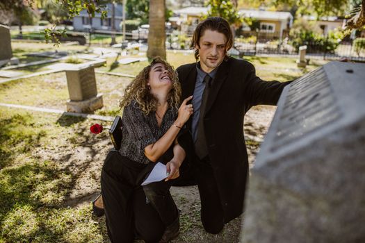 Man in Black Suit Jacket Sitting Beside Woman in Black and White Shirt and Black Pants