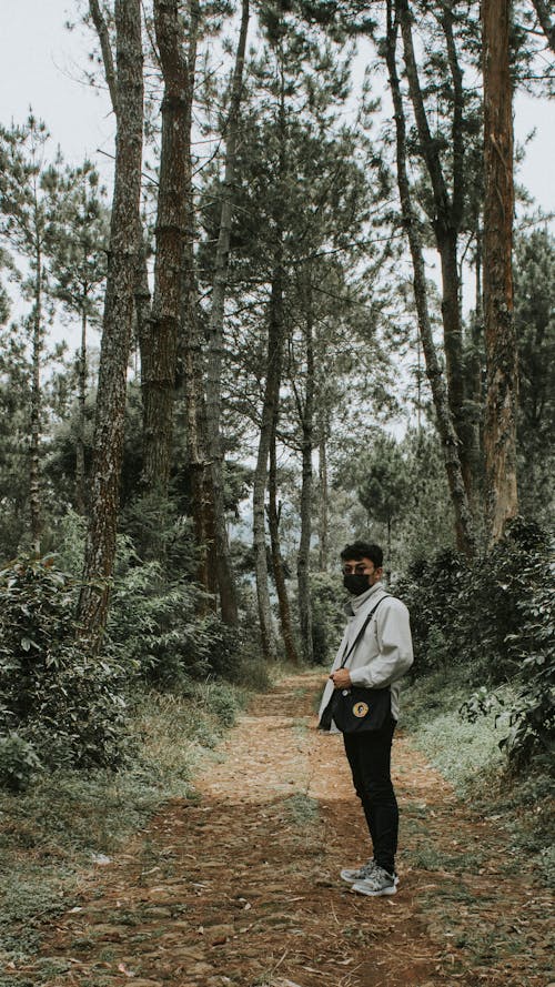 Man in White Long Sleeve Shirt Standing in between Trees