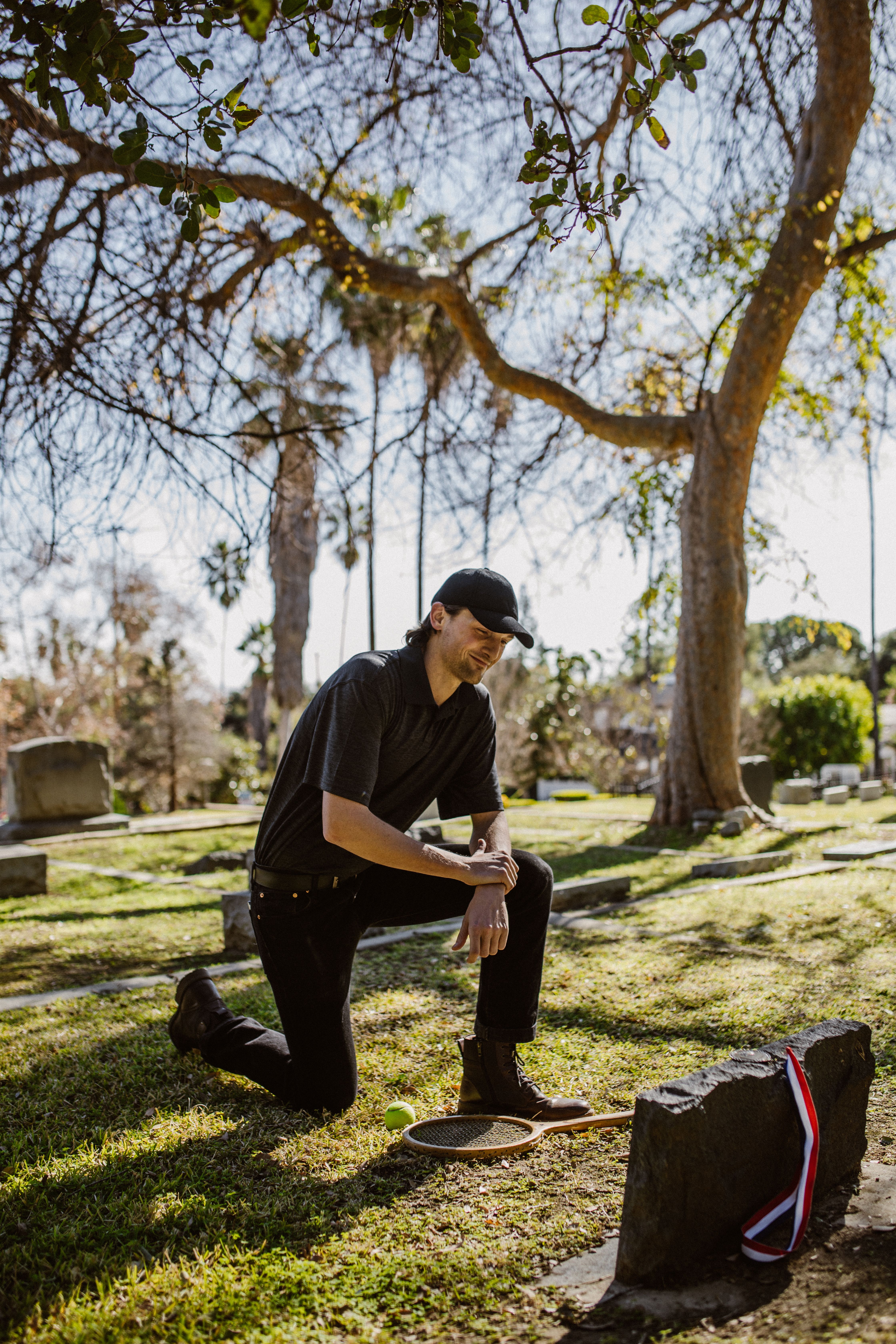 A Man Kneeling In Front of a Gravestone · Free Stock Photo