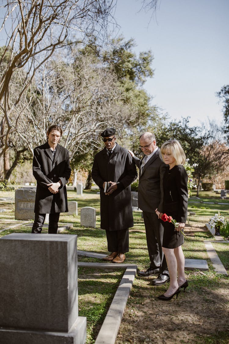 People Standing Before A Grave