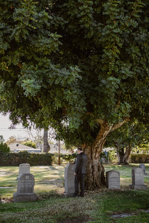 Lonely Man Standing in Front of a Gravestone