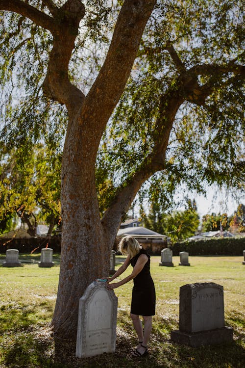 Lonely Woman in Black Dress Standing Near a Gravestone