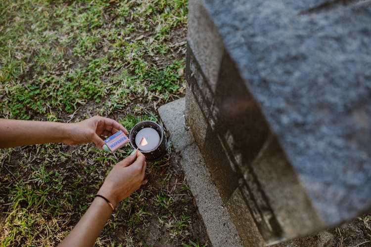 Person In Cemetery Lighting The Candle 