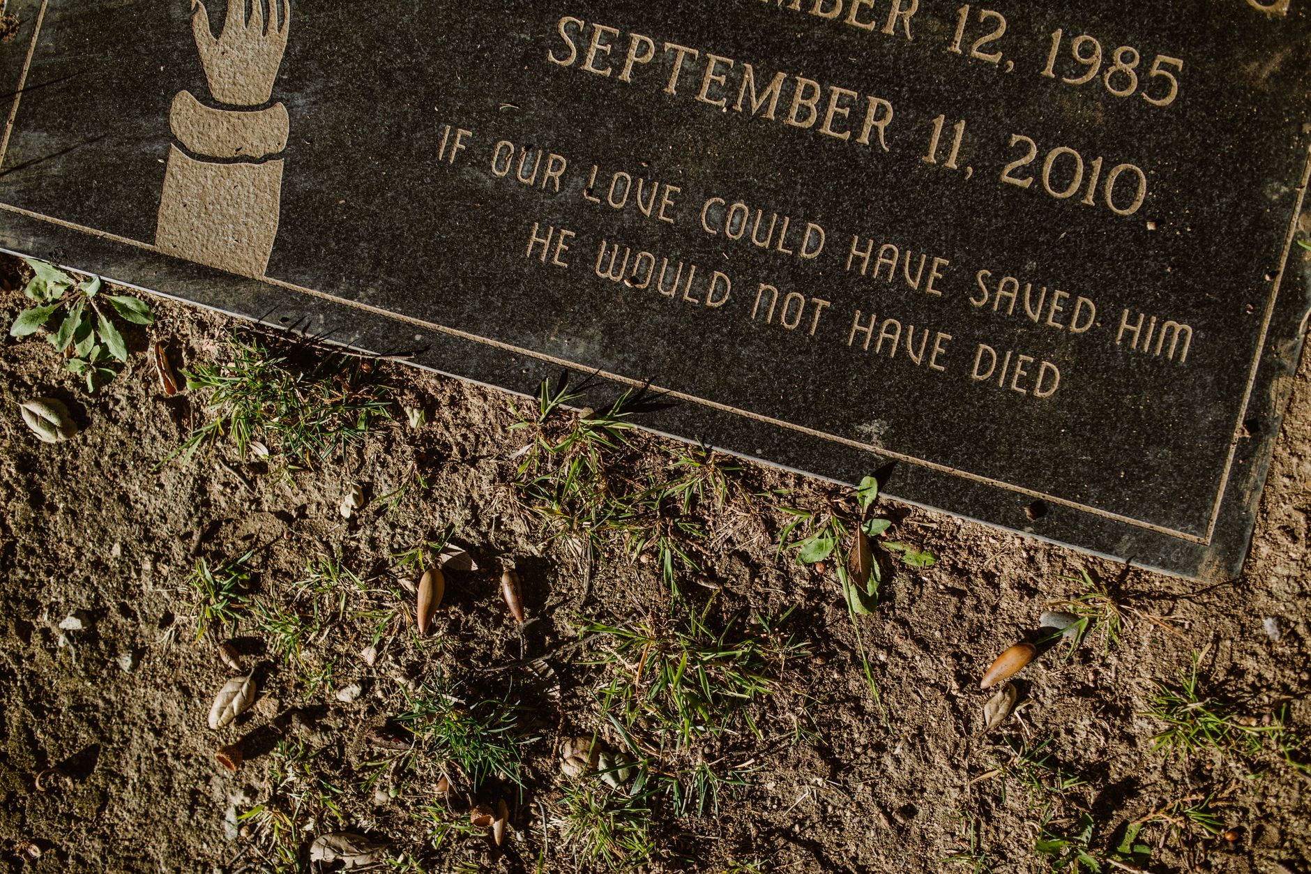 Close-up view of a gravestone with an engraved epitaph surrounded by greenery.