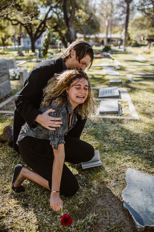 Free Woman Crying Beside a Man in a Cemetery Stock Photo