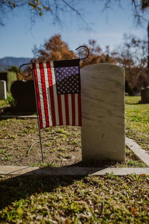 American  Flag Beside a Marble Headstone 