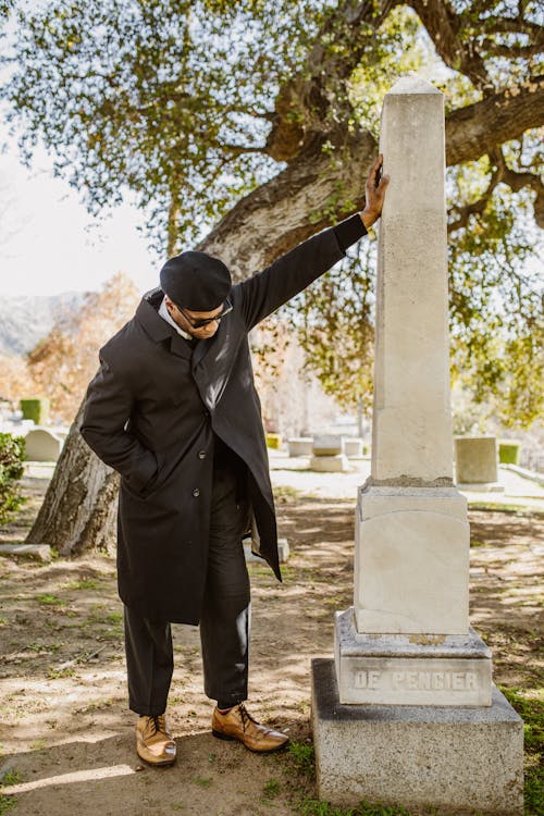 Free Man in Black Coat Standing Near a Concrete Headstone Stock Photo