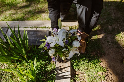 Man Placing a Bunch of Flowers on a Grave