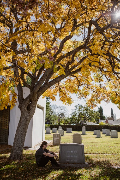 Photo of Man sitting in front of Gravestone